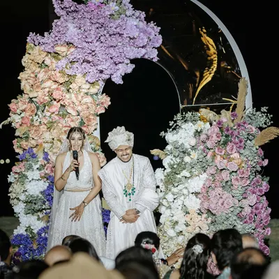 The couple addresses their guests after the wedding ceremony. This is a beautiful moment of gratitude and shared joy, with the stunning floral arch framing them perfectly.