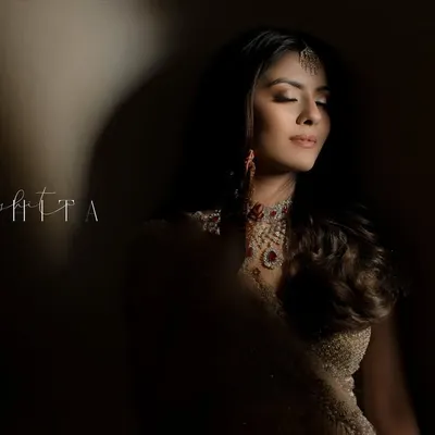 A moment of quiet contemplation for the bride. The dramatic play of light and shadow creates a powerful, artistic portrait that highlights her serene beauty and intricate jewelry.