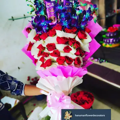 I love creating bouquets that are also a complete gift. This arrangement combines classic red and white roses with exotic blue orchids and includes Cadbury Silk chocolates nestled among the blooms, all wrapped beautifully.