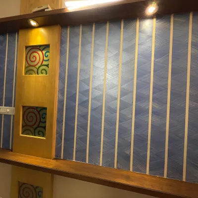 A finished accent wall combining multiple techniques. We used painter's tape to create a geometric pattern over a blue textured base, next to a wooden panel with custom art inserts.