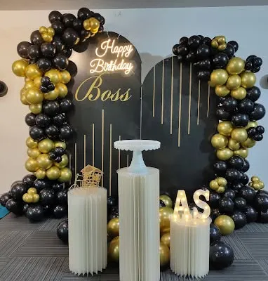 A premium decoration for a boss's birthday, designed to be the centerpiece of the office party. The setup includes a custom-arched backdrop with gold accents, a bright neon sign, and matching black and gold balloon garlands for a professional yet celebratory look.