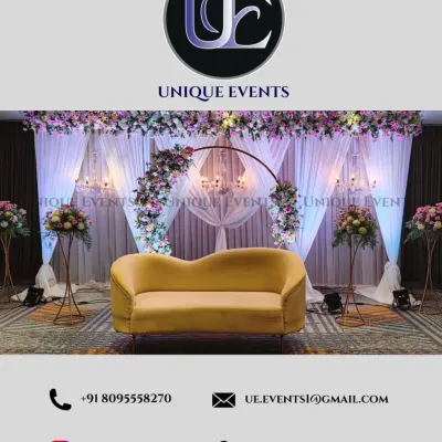 This modern stage setup for a reception features a stylish yellow sofa, a delicate floral arch, and elegant chandeliers against a backdrop of white curtains. The design is clean, romantic, and highly photogenic.