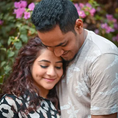 A close-up shot capturing a moment of pure contentment. The gentle lean and happy smiles show the comfort and security this couple finds in each other as they await their baby.