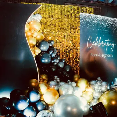 A modern and glamorous backdrop for Rani and Jignesh's celebration. The gold sequin wall provides a sparkling background, while the organic balloon garland in black, gold, and silver adds a touch of modern elegance.