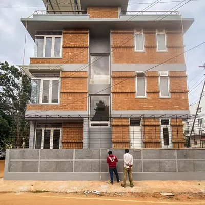 The facade of the Tripathy family home in Bangalore, built upon an existing foundation to minimize waste. The honest, brutalist facade features exposed mud blocks and jaali walls, showcasing our commitment to sustainable urban architecture.