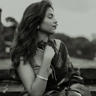 A serene black and white portrait. The model's calm expression and the soft focus on her tattoo create a personal and introspective mood, enhanced by the classic monochrome finish.