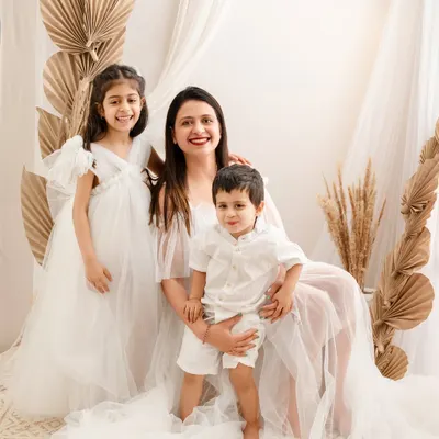 A serene portrait of a mother with her two children. The all-white theme and soft, dreamy setup create an angelic and timeless image that highlights their close bond.