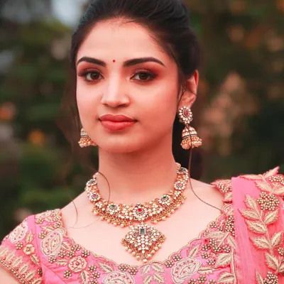 A beautiful outdoor portrait. The soft pink makeup looks fresh and vibrant in the natural light, perfect for a daytime celebration.