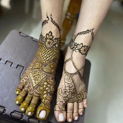 An example of asymmetrical feet mehendi, with one foot heavily decorated in a traditional style and the other featuring a lighter, jewellery-like design.