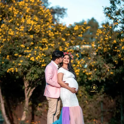A beautiful outdoor maternity portrait with the father-to-be lovingly embracing the mother-to-be. The colorful gown and natural backdrop of yellow flowers create a vibrant and joyful image.