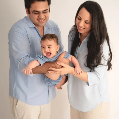 The pure joy of a baby's laughter is contagious. In this studio family portrait, the parents are completely focused on their happy baby, creating a candid and heartwarming shot.