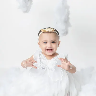 A little fairy with the happiest smile, sitting among the clouds. My studio is equipped with dreamy backdrops and props like these angel wings.