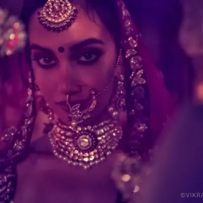 A captivating close-up from a bridal story for designers Shyamal & Bhumika. The intense gaze and moody, colorful lighting create a powerful image that highlights the emotion and artistry of the couture piece.