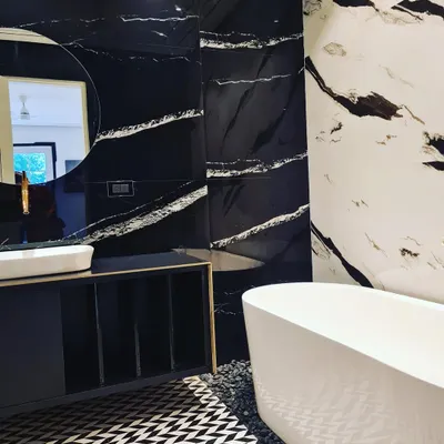 Rejuvenate your soul in this luxurious bathroom. It features a freestanding bathtub, black and white marble walls, and a geometric-patterned tile floor.