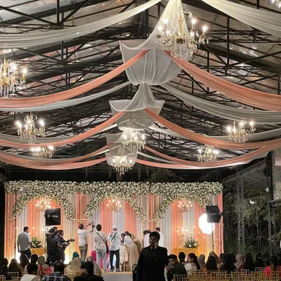 A beautifully decorated wedding hall for a Nikah reception. The elegant draping and chandeliers show that a blessed event can also be a grand and memorable celebration for the entire family.