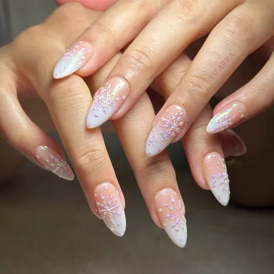 Sprinkled with stardust. A full view of these elegant almond extensions with a milky white ombre and delicate, sparkling snowflake details.