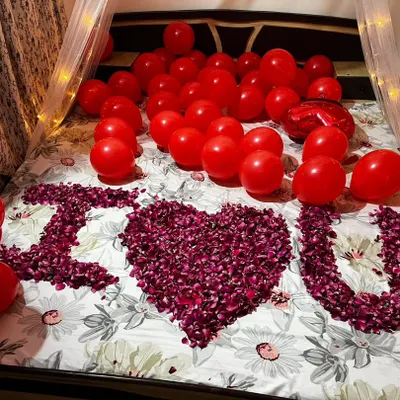 A classic romantic room surprise I set up for an anniversary. This includes a fairy light canopy, red balloons covering the bed, and a personal message spelled out in fresh rose petals.