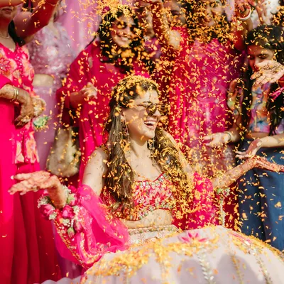 A bride's joyful laugh as she is showered with flower petals during her Haldi ceremony, a perfect candid moment.