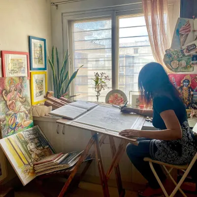 This is my happy place, my art studio at home. This candid photo captures me completely absorbed in my work, sketching out a new idea at my desk.