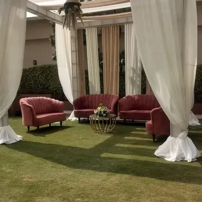 A cozy lounge seating cluster created for an outdoor event. The pink velvet sofas and a central coffee table provide a perfect spot for guests to chat and relax.