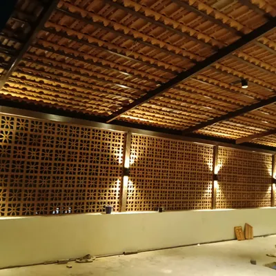 A finished terrace project at night, showcasing how a terracotta jali wall can be enhanced with lighting. The up-and-down lights create a warm, inviting ambiance and highlight the intricate patterns of the screen.