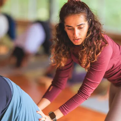 Providing a gentle adjustment in a downward-facing dog. My approach is hands-on, helping you find the right alignment for your body so you can experience the pose more deeply and safely.