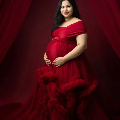 A stunning solo portrait featuring one of our elegant maternity gowns. The rich red color and ruffled details of the dress make for a truly memorable and glamorous shot.