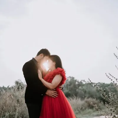 A classic romantic silhouette against a bright sky. The sun peeking through as the couple embraces creates a magical, backlit effect that is both dramatic and intimate.