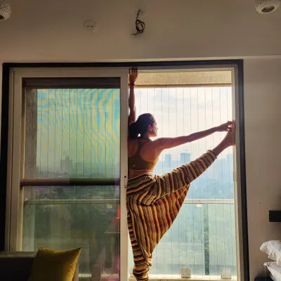 This is a standing leg raise, a pose that challenges balance and flexibility. My teaching has evolved to focus more on how a pose feels for the individual student rather than chasing perfect alignment.