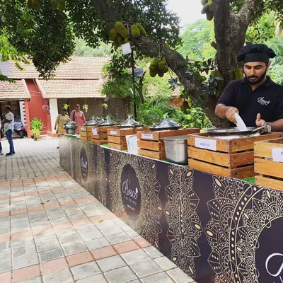 A typical outdoor catering setup under a large jackfruit tree. We can adapt our stations to any environment, ensuring the food service is smooth and professional.