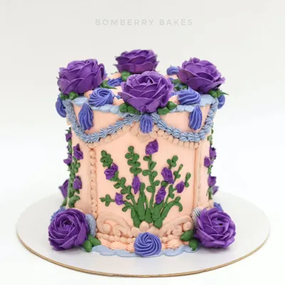A beautiful vintage-style buttercream cake with a peach base and intricate purple floral piping. This Lambeth-style cake is a timeless classic.