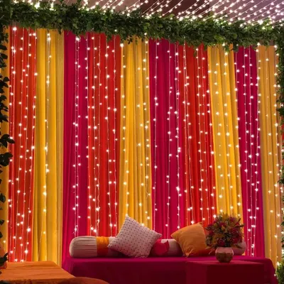 A vibrant and festive backdrop for a Haldi or Mehndi ceremony. I used curtains in bright yellow and pink, interwoven with strings of fairy lights, to create this joyful and photo-perfect seating area.