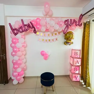 This is a classic "baby girl" welcome home decoration. It features a pink and white balloon arch, "baby girl" foil letters, a "Welcome Baby" banner, and illuminated "BABY" display boxes. It creates a perfect corner for photos.