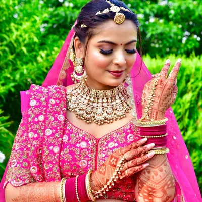 A joyful and candid bridal portrait. The bride's happy expression and detailed henna are the focus of this close-up, captured in a beautiful outdoor garden setting.