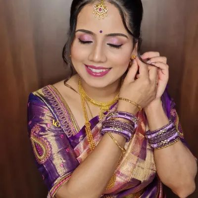 A lovely candid moment of Aparna adjusting her earring. This pose highlights her elegant hairstyle, the maang tikka, and the flawless finish of her makeup.