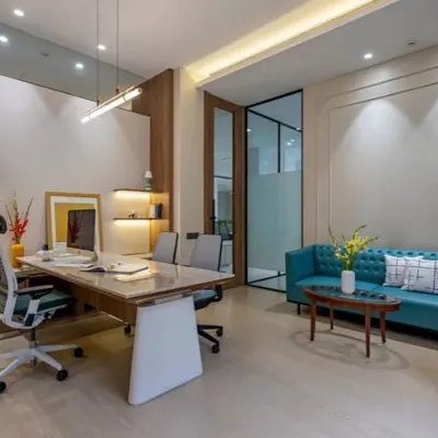 This executive office balances work and comfort. It features a large desk for productivity, a comfortable sofa for informal meetings, and custom shelving, all tied together with a pop of color from the turquoise sofa.