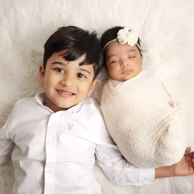 A perfect shot of a proud big brother smiling next to his sleeping newborn sibling. I use a soft, fluffy rug to ensure the babies are comfortable and safe during these sibling photoshoots.