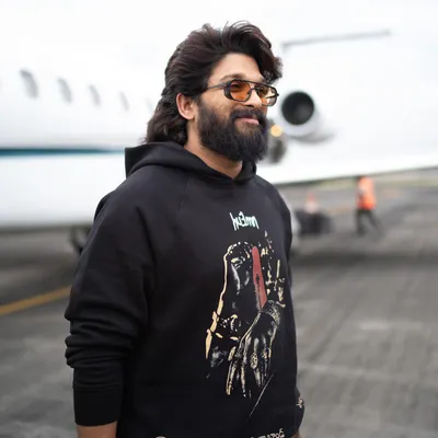Allu Arjun stepping off a private jet in a custom 'Pushpa' themed hoodie from Huemn. This is how we do promotion style: cool, comfortable, and completely on-brand.