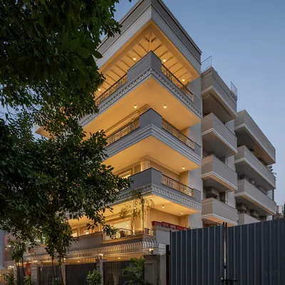 The KAIRA residence viewed from the street at dusk. The facade's neo-classical details, including layered cornices and decorative railings, are highlighted by integrated lighting, creating a warm and inviting presence.