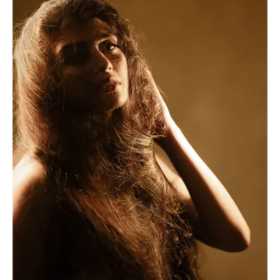 A raw, artistic portrait using a single light source to create deep shadows and highlight the texture of the hair. This is about capturing a feeling, not just a likeness.