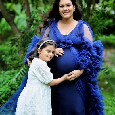 An outdoor maternity portrait surrounded by lush greenery. The royal blue gown beautifully complements the natural setting, creating a serene and powerful image of motherhood.