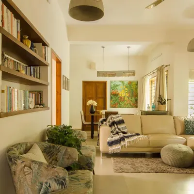 The living room of a renovated home, where floating bookshelves were crafted from the house's old wooden doors. By stripping away the old polish, I revealed the beautiful seasoned teak underneath and repurposed it to add warmth and history to the space.