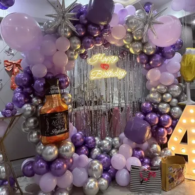 A full view of a stylish 40th birthday decoration. The purple, lavender, and silver balloon ring, shimmer backdrop, neon sign, and marquee numbers create a complete and elegant look.