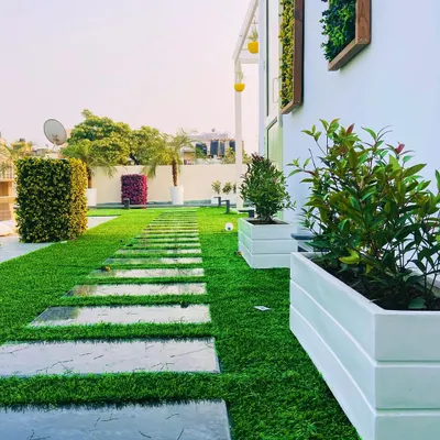 This rooftop garden path features large, polished stone slabs set into a bed of high-quality artificial turf. This combination creates a clean, contemporary look that is low-maintenance and provides a practical, stylish walkway through the space.