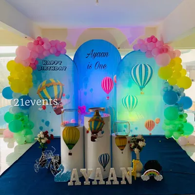 A dreamy hot air balloon theme with multiple arched backdrops creating a sky-like scene. The pastel balloons and themed pedestals complete the look for a magical first birthday.
