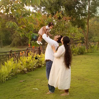 A father joyfully lifts his daughter into the air as her mother looks on. We capture these spontaneous moments of happiness during our outdoor family photoshoots.