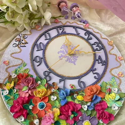 A full view of a 14-inch custom wall clock with a lavender base and a cascade of multi-colored flowers. The unique numeral design adds a modern touch to this floral timepiece, perfect for a bedroom or study.