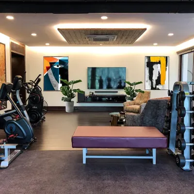 A full view of the private gym and lounge area. The design integrates the workout equipment with a media and seating zone, making it a versatile space for both fitness and relaxation.