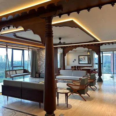 Another view of the Embassy Lake Terraces residence, showing how the traditional wooden structure defines the living and dining areas. The design allows for an open feel while creating distinct zones, with a clear sightline to the oonjal and window views.