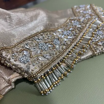 Tassels and crystals. A close-up of a heavily embellished sleeve cuff, featuring intricate crystal work and bugle bead tassels for a touch of glamour.